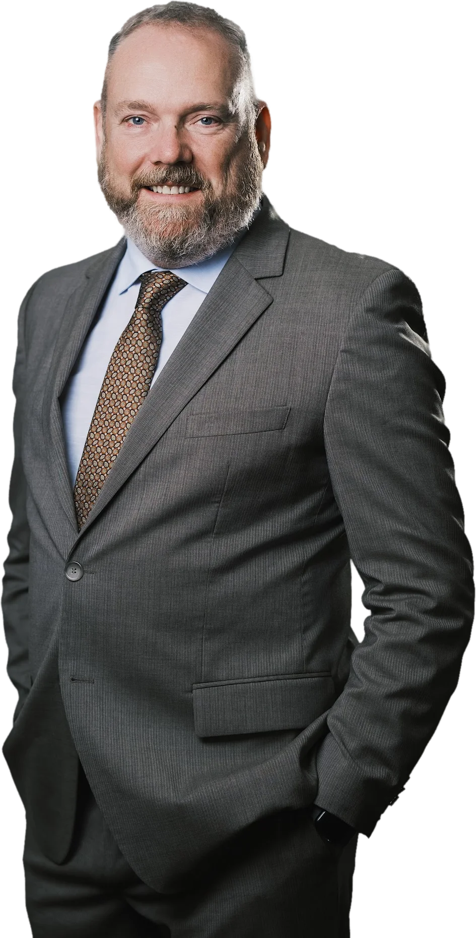 Neil Gannon smiling, in a charcoal suit with hands in pockets